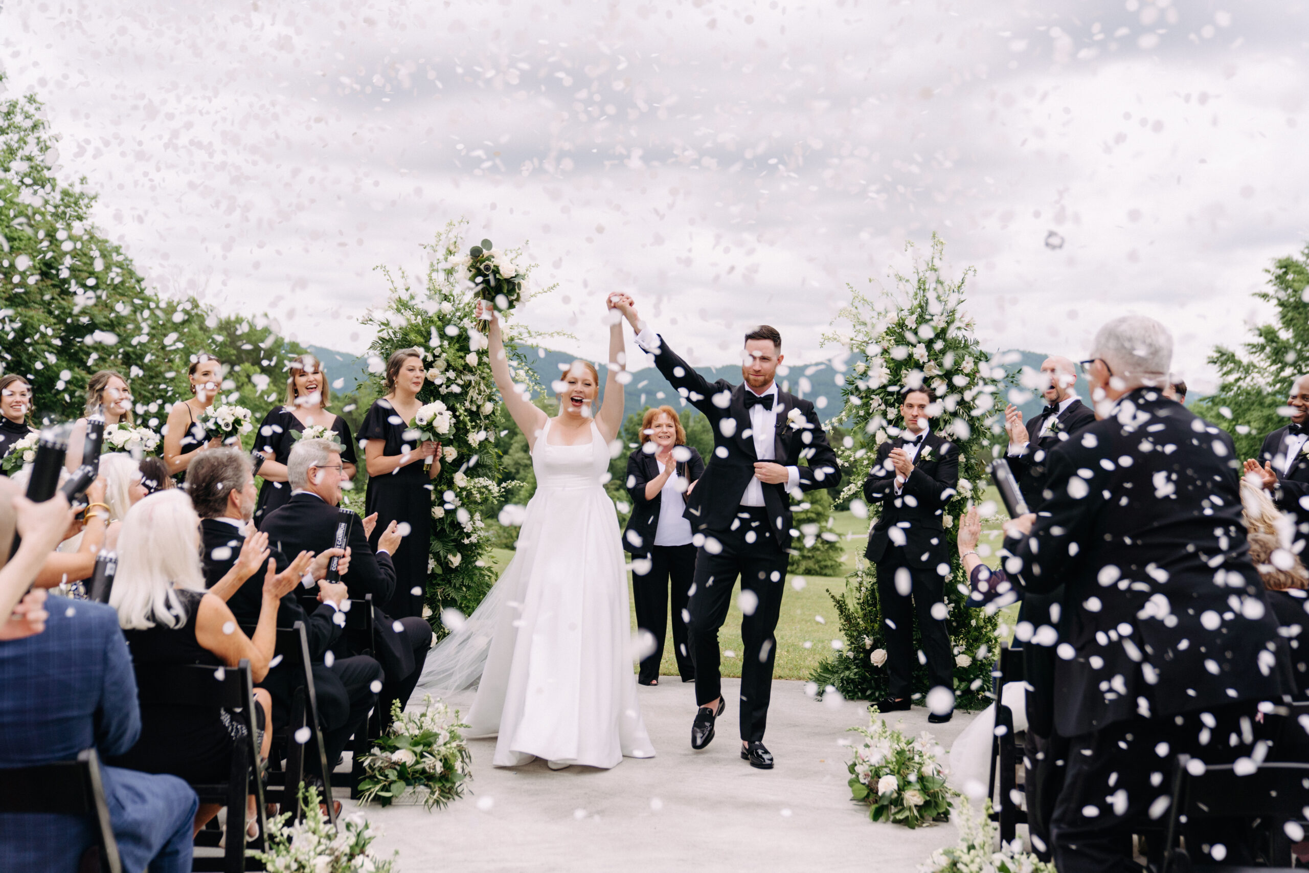 bride and groom cheered on by their guests as they exit the ceremony
